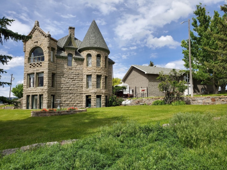 The Castle museum today, a stone Victorian mansion with a round turret on a green hillside